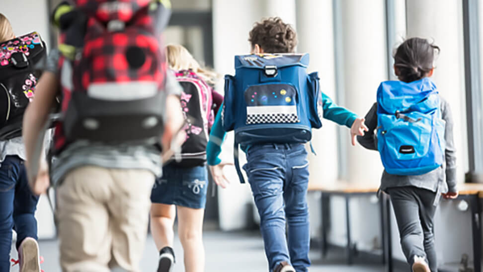 Kinderen met rugzak rennen door schoolgang